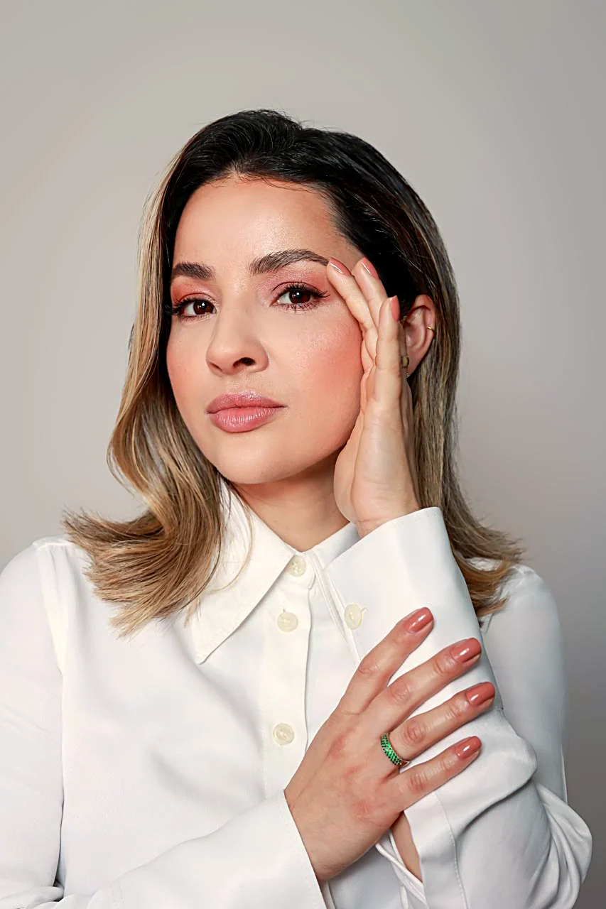 Retrato da Dra. Luciane Lopes olhando para a câmera, com a mão apoiada no rosto